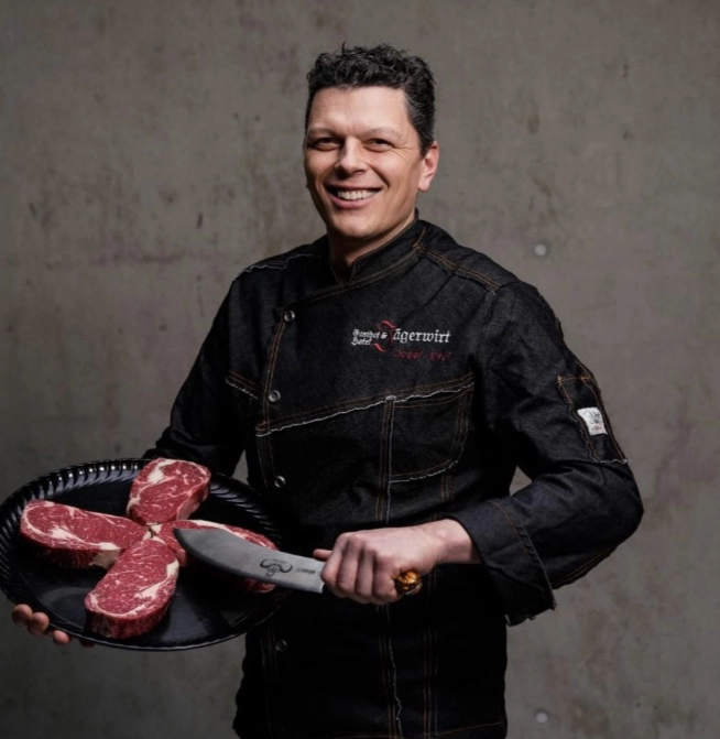 Josef Meyr hält Messer und geschnittene Fleischstücke