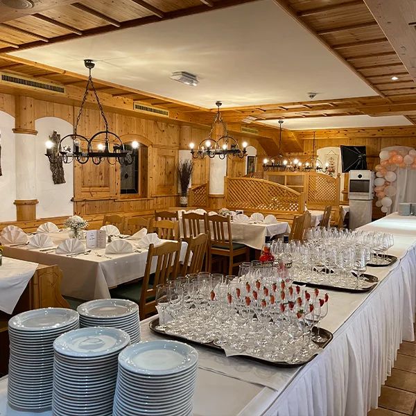 gestapelte Teller und Gläser auf weiß gedeckten Tischen in Gastraum