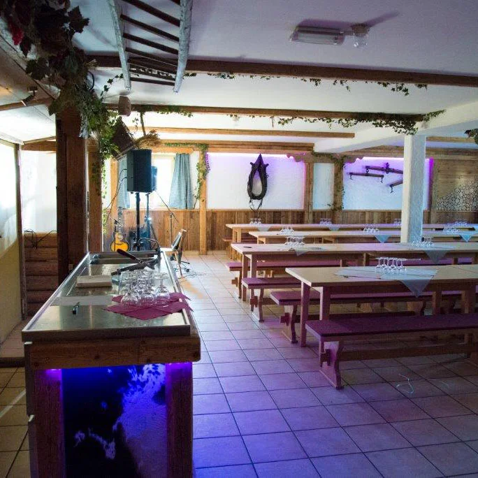 Ein Raum mit Tischen und Bänken und Tresen, in lila beleuchtet